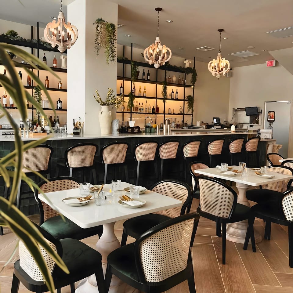 Lantern House Kitchen & Bar's elegant dining room with a long bar, chandeliers, and set tables.